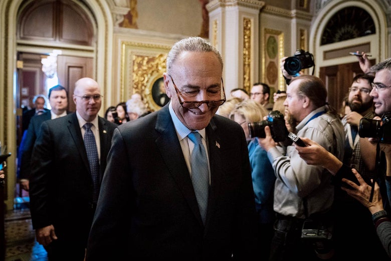 Chuck Schumer smiles as he passes a crowd of photographers and reporters at the Capitol.
